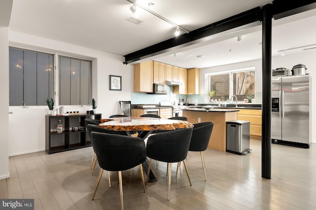 dining room with sink, rail lighting, beam ceiling, and light wood-type flooring