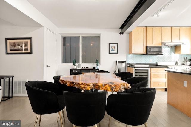 dining area with light wood-type flooring, track lighting, and wine cooler