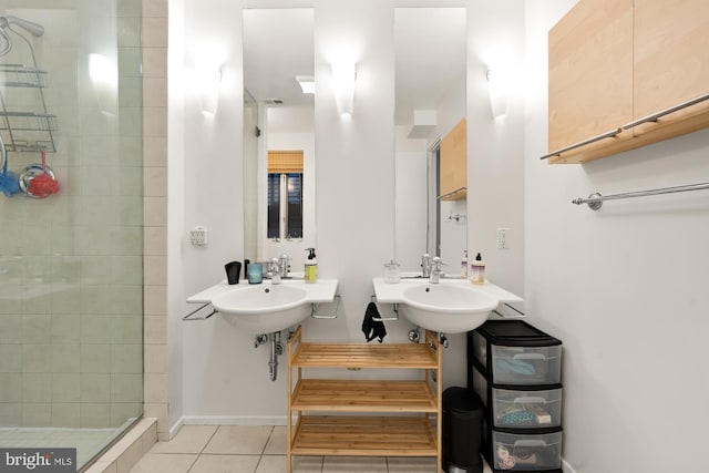 bathroom featuring dual sinks, tiled shower, and tile patterned floors