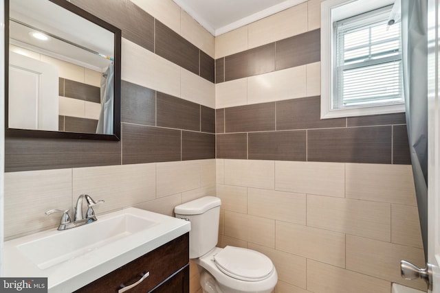 bathroom with curtained shower, toilet, tile walls, and vanity