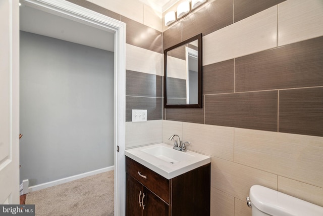 bathroom featuring toilet, vanity, and tile walls