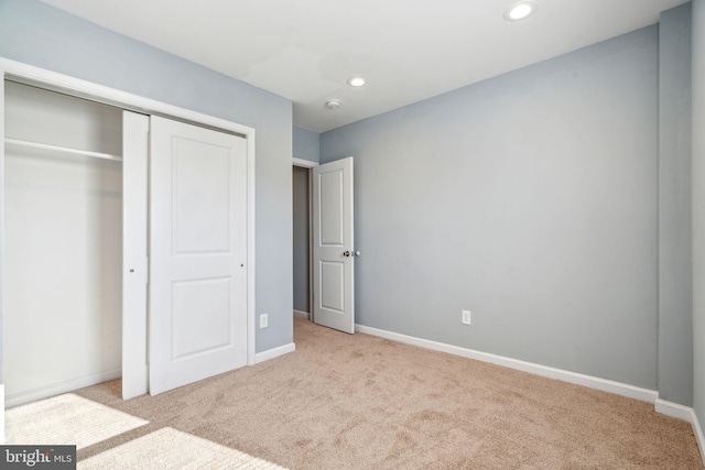 unfurnished bedroom with a closet and light colored carpet