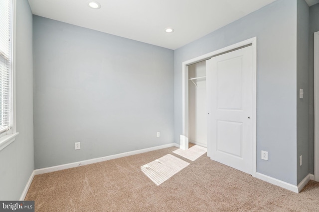 unfurnished bedroom featuring a closet and light colored carpet