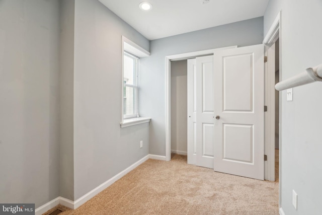 unfurnished bedroom with light colored carpet and a closet