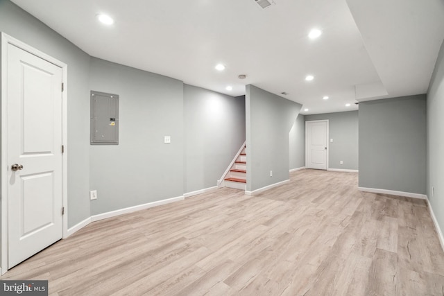 basement with light wood-type flooring and electric panel