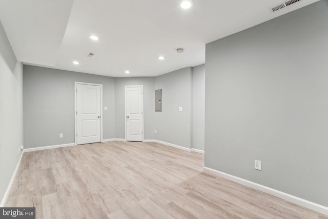 unfurnished room featuring electric panel and light hardwood / wood-style flooring