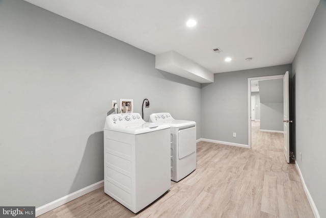 clothes washing area featuring light hardwood / wood-style floors and washer and dryer