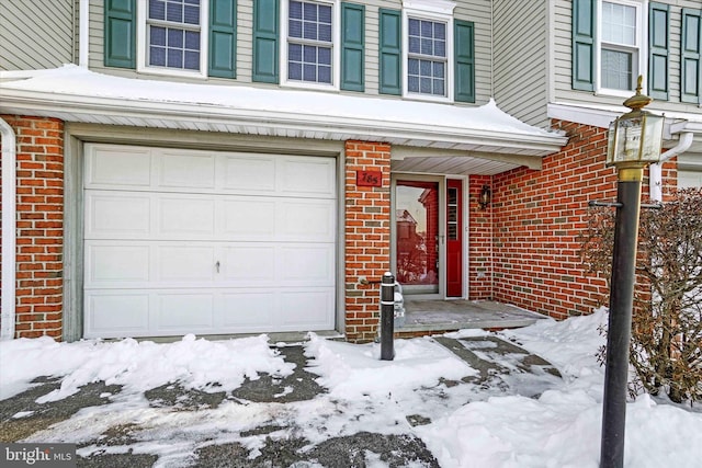 snow covered property entrance with a garage