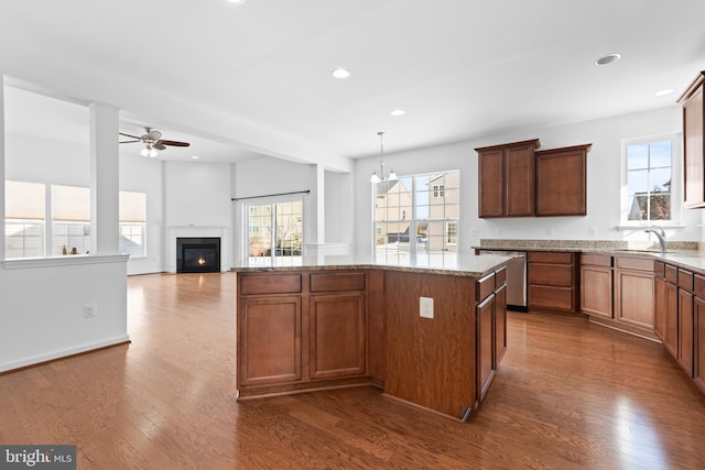 kitchen with sink, hanging light fixtures, dark hardwood / wood-style floors, a center island, and stainless steel dishwasher