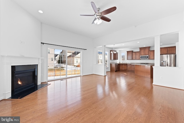 unfurnished living room with plenty of natural light, ceiling fan, and light wood-type flooring