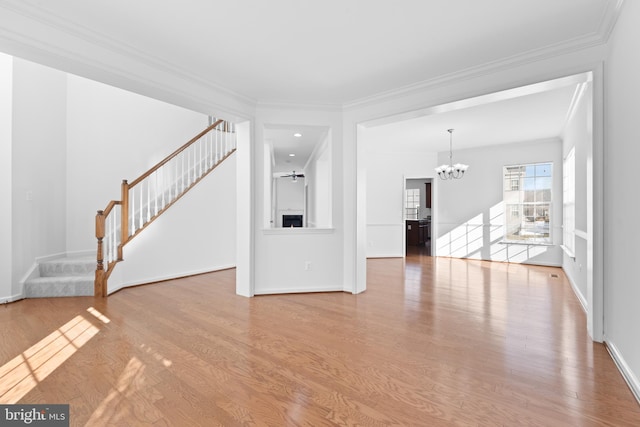 unfurnished living room featuring ornamental molding, a chandelier, and light hardwood / wood-style floors