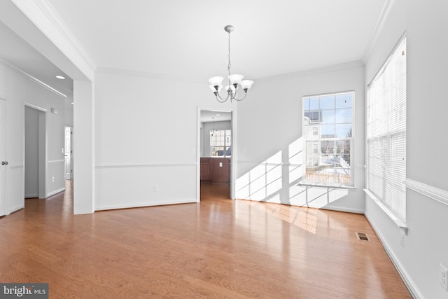 empty room with an inviting chandelier, crown molding, and hardwood / wood-style flooring