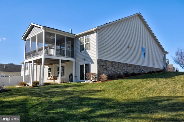 back of house featuring a lawn, a sunroom, and ceiling fan