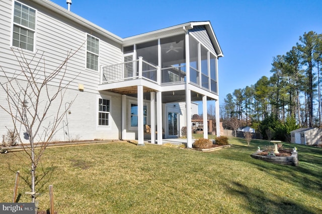 rear view of property featuring a storage unit, a patio area, a sunroom, and a lawn