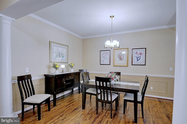 dining area featuring an inviting chandelier, ornamental molding, light hardwood / wood-style floors, and decorative columns