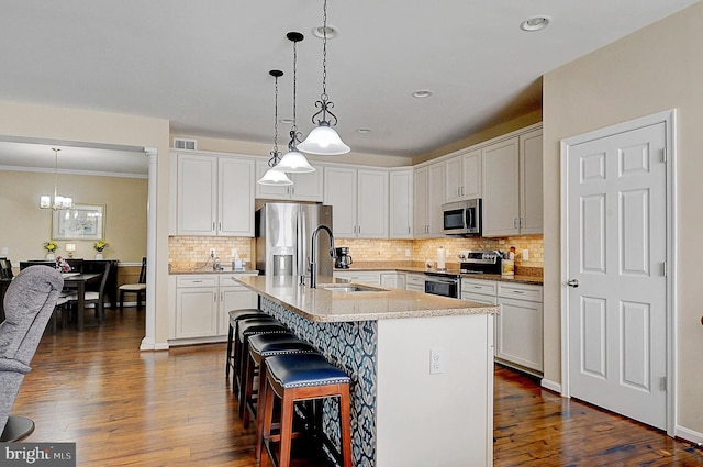 kitchen with appliances with stainless steel finishes, white cabinetry, an island with sink, sink, and a breakfast bar area