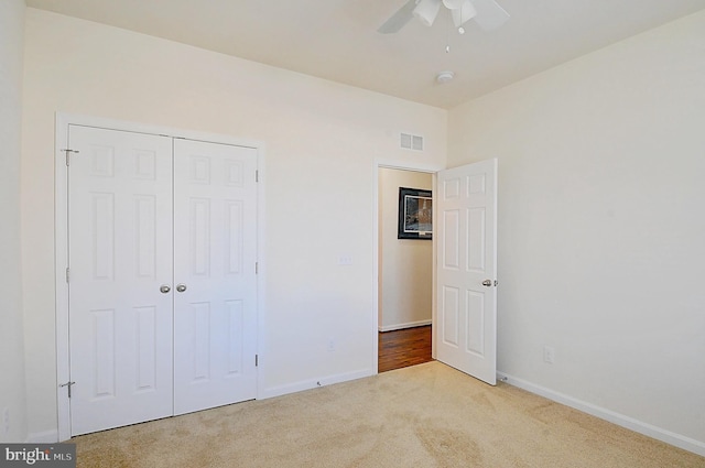 unfurnished bedroom with light carpet, a closet, and ceiling fan