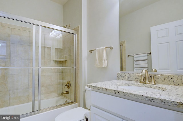 full bathroom with enclosed tub / shower combo, vanity, and toilet