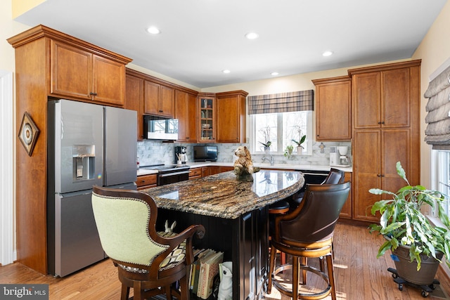 kitchen featuring a center island, stainless steel fridge with ice dispenser, decorative backsplash, a breakfast bar, and dark stone counters