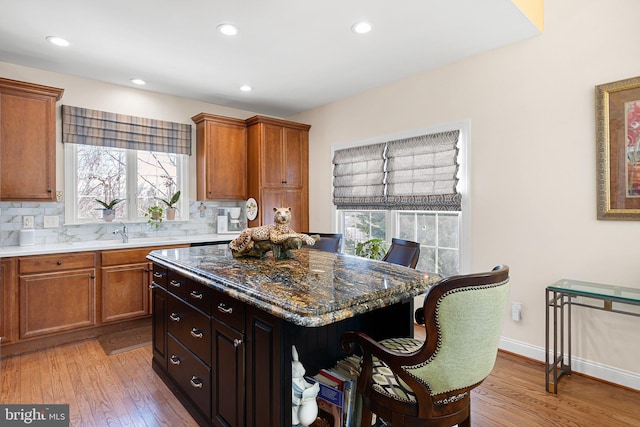 kitchen with plenty of natural light, tasteful backsplash, dark hardwood / wood-style floors, dark stone countertops, and a kitchen island