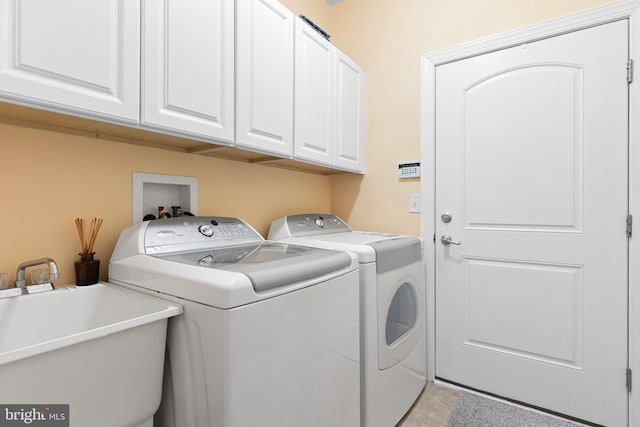 clothes washing area featuring sink, cabinets, and washer and dryer