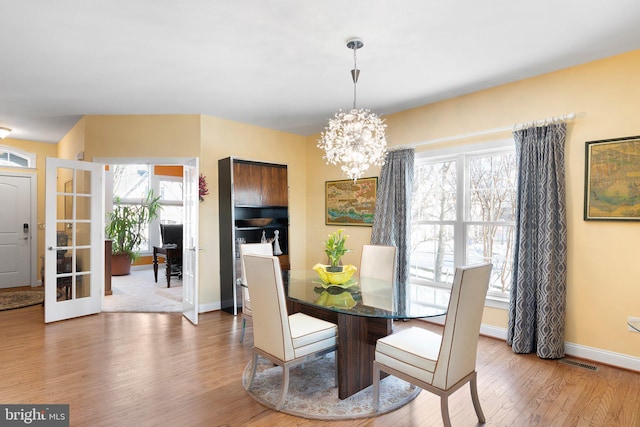 dining area with a healthy amount of sunlight, an inviting chandelier, and wood-type flooring