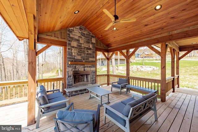 wooden terrace featuring ceiling fan and an outdoor living space with a fireplace