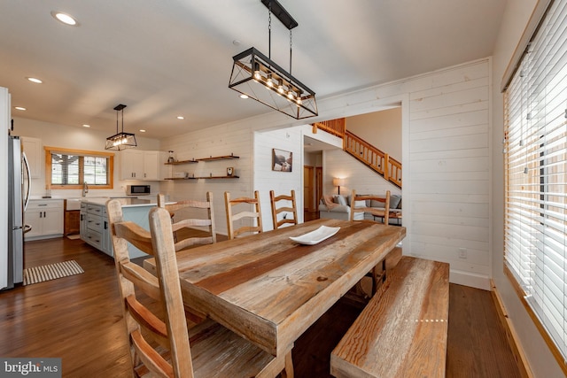 dining space featuring dark hardwood / wood-style floors, sink, and wooden walls