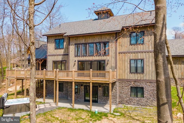 rear view of house featuring a hot tub, a deck, and a patio area