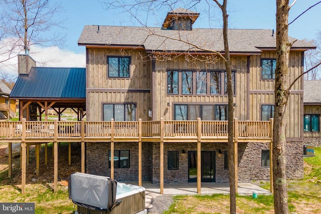 back of house with a hot tub, a patio, and a wooden deck