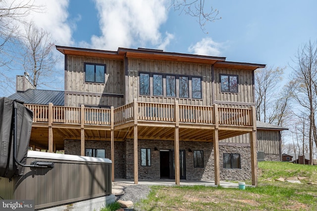 back of house with a wooden deck, a hot tub, and a patio area