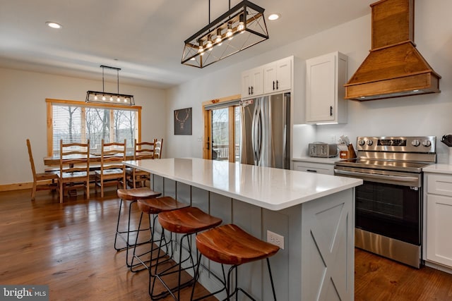 kitchen with hanging light fixtures, stainless steel appliances, white cabinets, a kitchen island, and custom exhaust hood