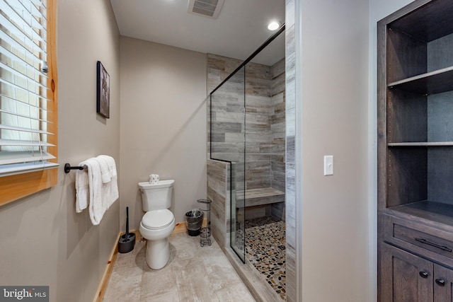 bathroom with a shower with shower door and toilet