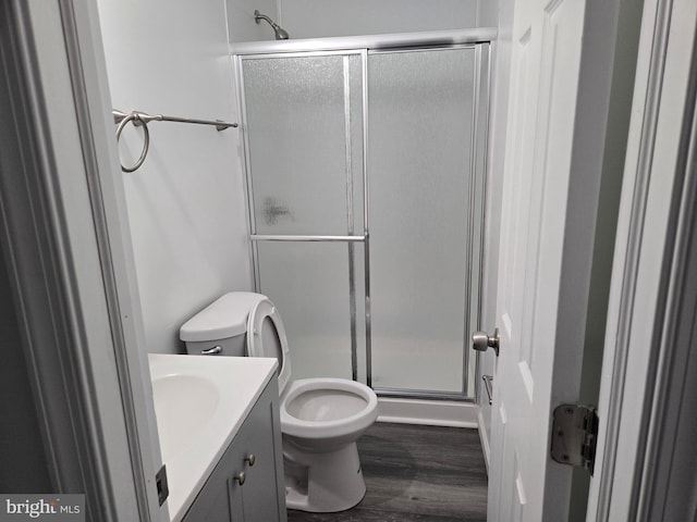 full bath featuring toilet, vanity, a shower stall, and wood finished floors