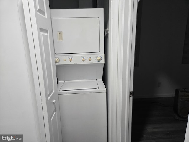 laundry room with stacked washer and dryer, laundry area, baseboards, and wood finished floors