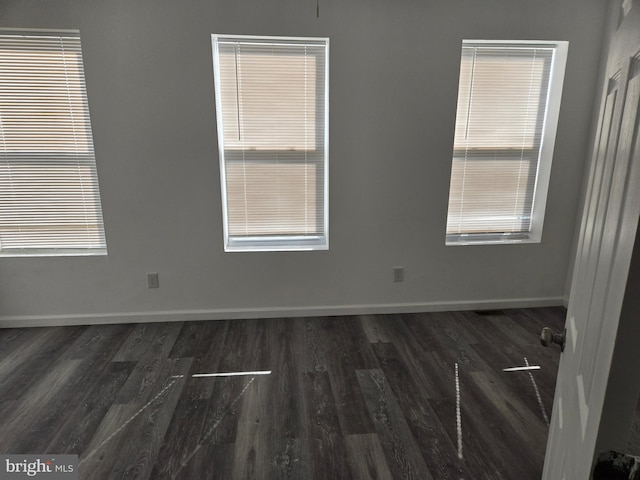 empty room featuring dark wood finished floors and baseboards