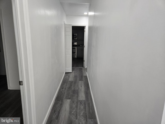 hall featuring dark wood-style flooring and baseboards