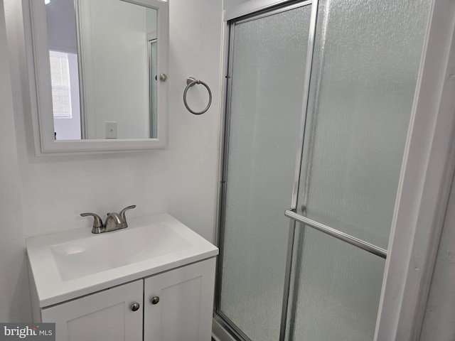 bathroom featuring a shower with door and vanity