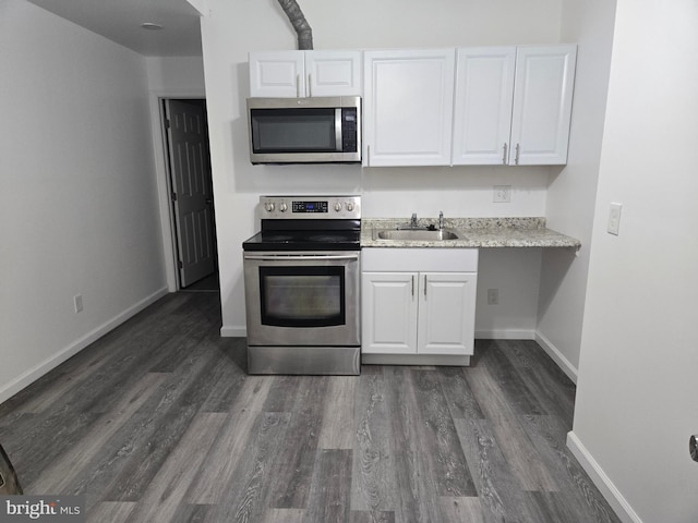 kitchen with baseboards, white cabinets, appliances with stainless steel finishes, dark wood-style flooring, and a sink