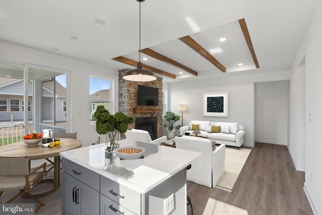 kitchen with wood-type flooring, decorative light fixtures, gray cabinetry, a brick fireplace, and a center island