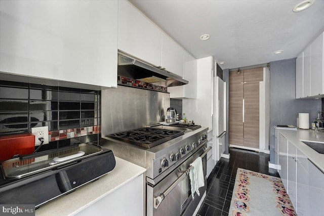 kitchen with backsplash, high end stainless steel range, sink, and white cabinets