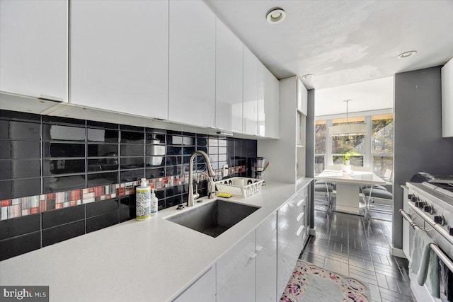 kitchen featuring sink, pendant lighting, white cabinetry, high end stainless steel range oven, and backsplash