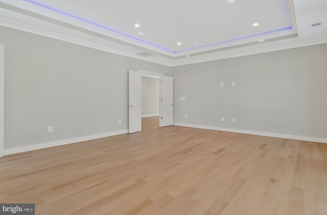 unfurnished bedroom with light hardwood / wood-style floors, crown molding, and a raised ceiling