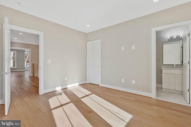 unfurnished bedroom featuring sink, ensuite bath, and light wood-type flooring