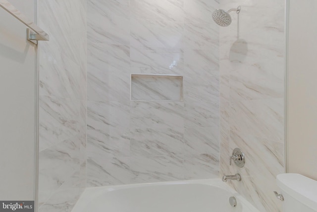 bathroom featuring toilet and tiled shower / bath