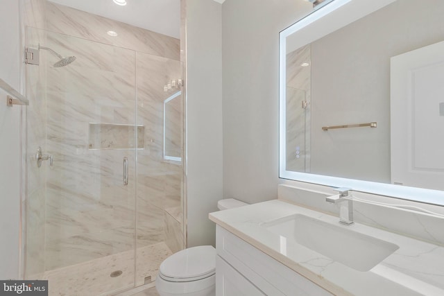 bathroom featuring toilet, a shower with shower door, and vanity