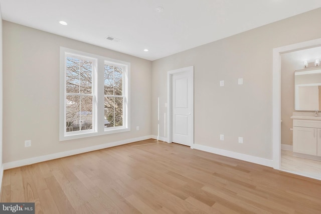 unfurnished bedroom with ensuite bathroom and light hardwood / wood-style flooring