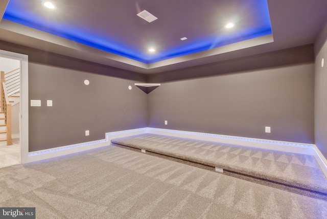 home theater room featuring light colored carpet and a tray ceiling