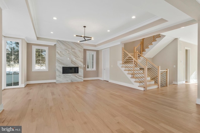 unfurnished living room featuring light hardwood / wood-style floors, a chandelier, ornamental molding, and a premium fireplace