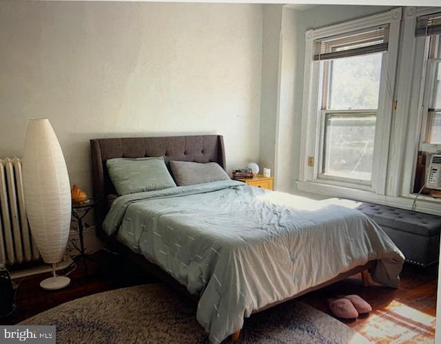 bedroom with hardwood / wood-style flooring and radiator heating unit